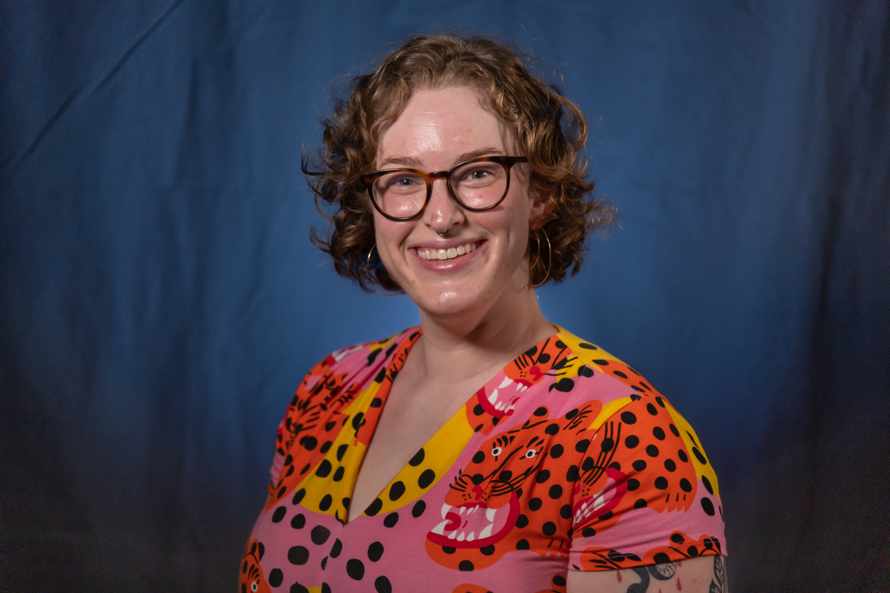 headshot of curly haired blonde woman in glasses and a bright colored blouse