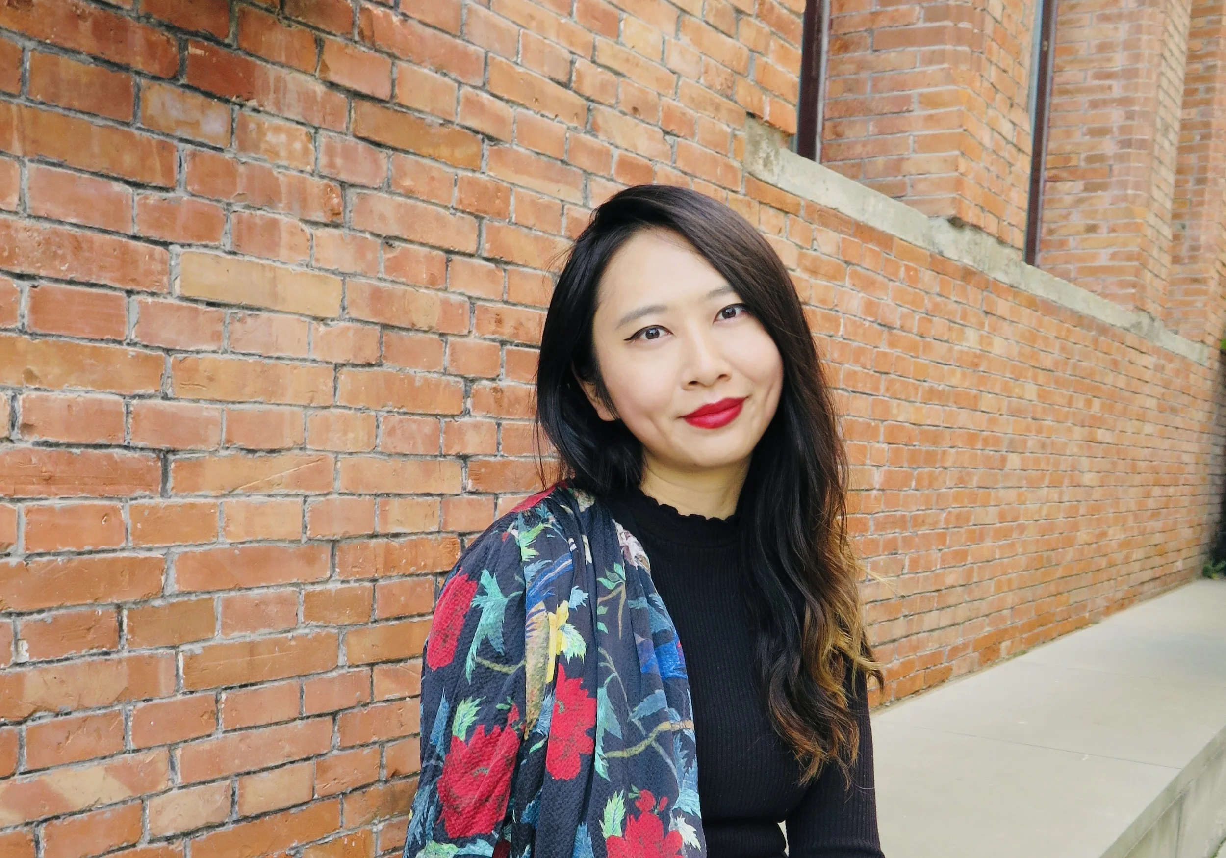 Posed photo of asian woman against brick background
